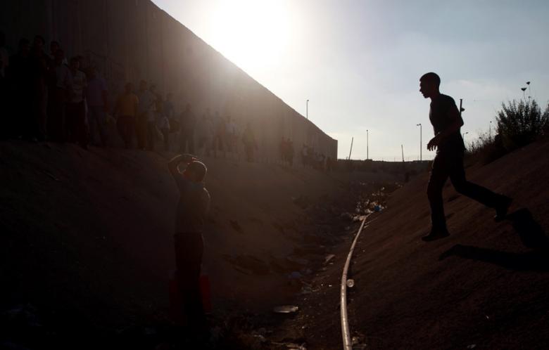 A Palestinian youth is silhouetted against the light as Muslim worshippers walked at sunset on 4 August 2013 towards Israel's Qalandia checkpoint between Ramallah and Jerusalem(Photo: AFP - Abbas Momani)