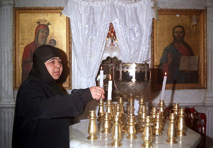 A Syrian nun lights candles inside the historical church of Mar Taqla in the village of Maaloula north of Damascus (AFP Photo)